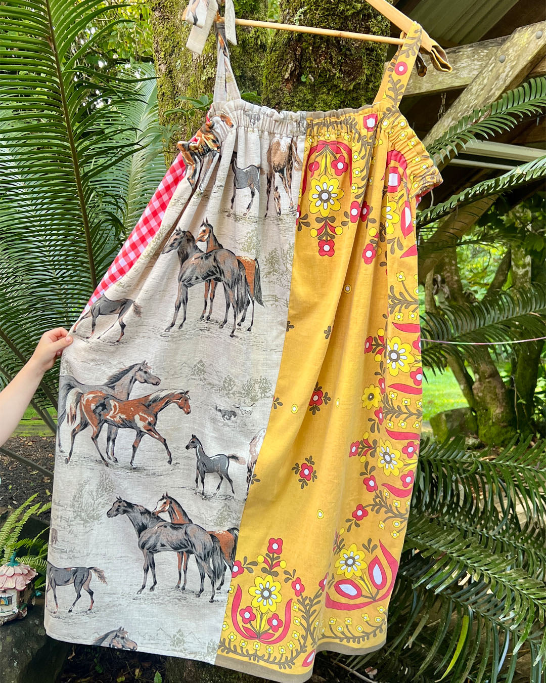 Lucky horse plus size, one size, easywear, oversize tea party dress with adjustable straps, elasticised neckline and upcycled, recycled, vintage, heirloom, patchwork fabrics. One fabric depicts lucky horses and another is bright mustard retro flowers with red accents.