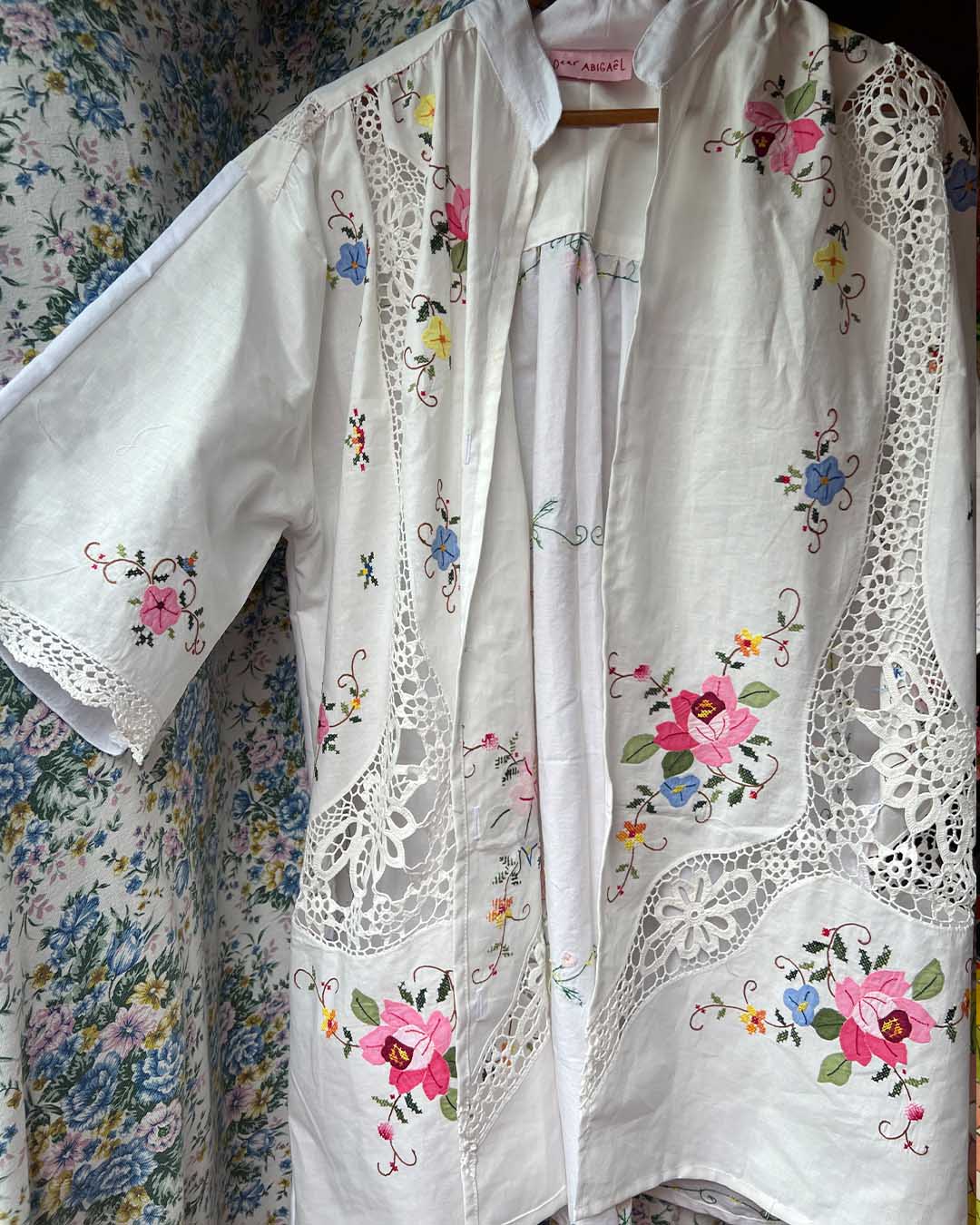 White embroidered blouse with floral patterns on a floral background