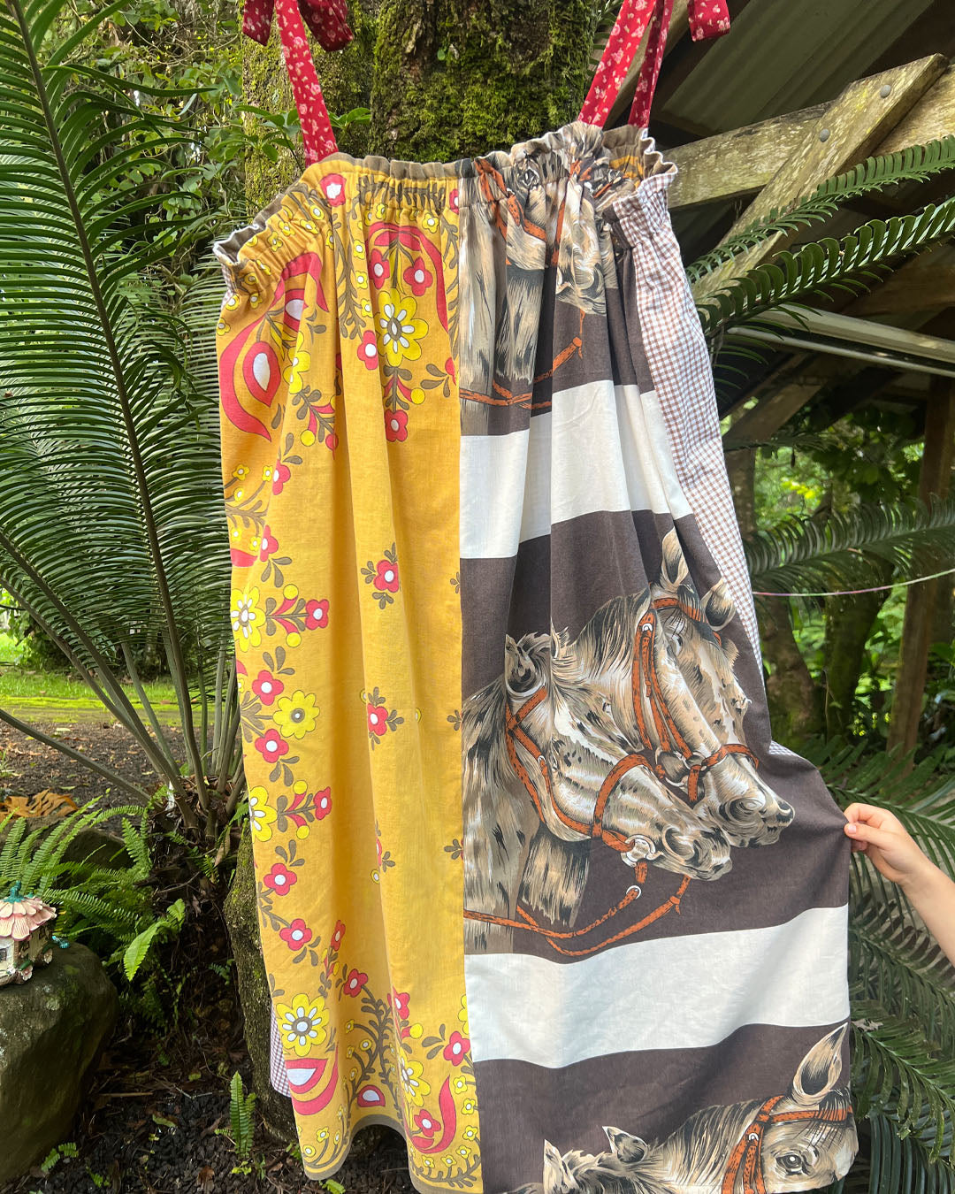 Lucky horse plus size, one size, easywear, oversize tea party dress with adjustable straps, elasticised neckline and upcycled, recycled, vintage, heirloom, patchwork fabrics. One fabric depicts lucky horses and another is bright mustard retro flowers with red accents.