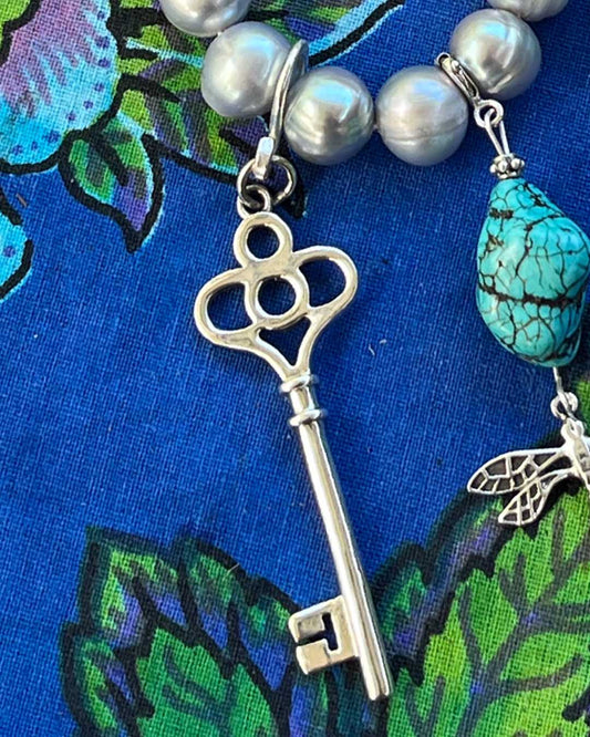 Sterling silver key talisman bringing good fortune and intuitive magic. Photographed with turquoise and sterling silver talismans on a cultured
Freshwater pearl necklace 