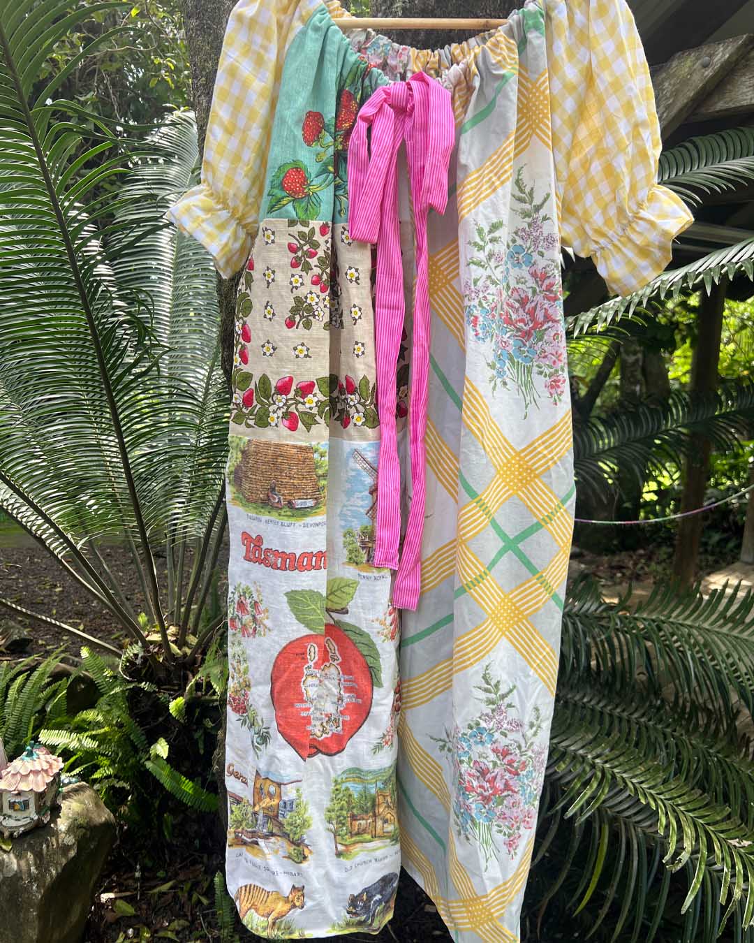 Colorful patchwork dress with floral and patterned design hanging outdoors.