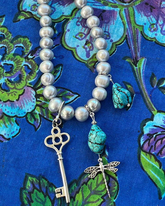 Sterling silver key talisman bringing good fortune and intuitive magic. Photographed with turquoise and sterling silver talismans on a cultured
Freshwater pearl necklace 