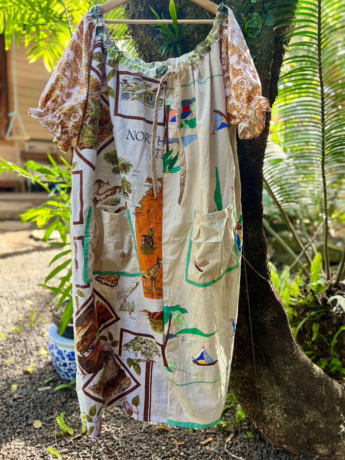 Vibrant one size, plus size smock to suit many different bodies, size inclusive, vintage patchwork smock hanging in a beautiful spring fashion garden