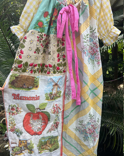 Colorful asmock with 'Tasmania' design held by a person against a green leafy background