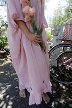 Load image into Gallery viewer, Woman in a one size, plus size, free size, pink dress with silver lurex strip and indian mirrorwork holding flowers in an outdoor , seaside setting