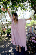 Load image into Gallery viewer, Woman in a one size, plus size, free size, pink dress with silver lurex strip and indian mirrorwork holding flowers in an outdoor , seaside setting