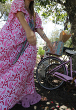 Load image into Gallery viewer, Person in a pink floral dress standing next to a pink bicycle outdoors.