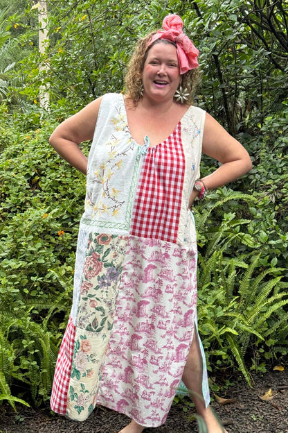 Woman wearing a patchwork dress with floral and checkered patterns in a garden setting.