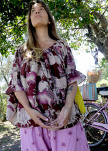 Load image into Gallery viewer, Woman wearing a pink and chartreuse handblock patterned top with holy cow motif and purple pants standing outdoors with trees and plants in the background. A perfect Christmas Fashion Outfit and Black Friday Sale