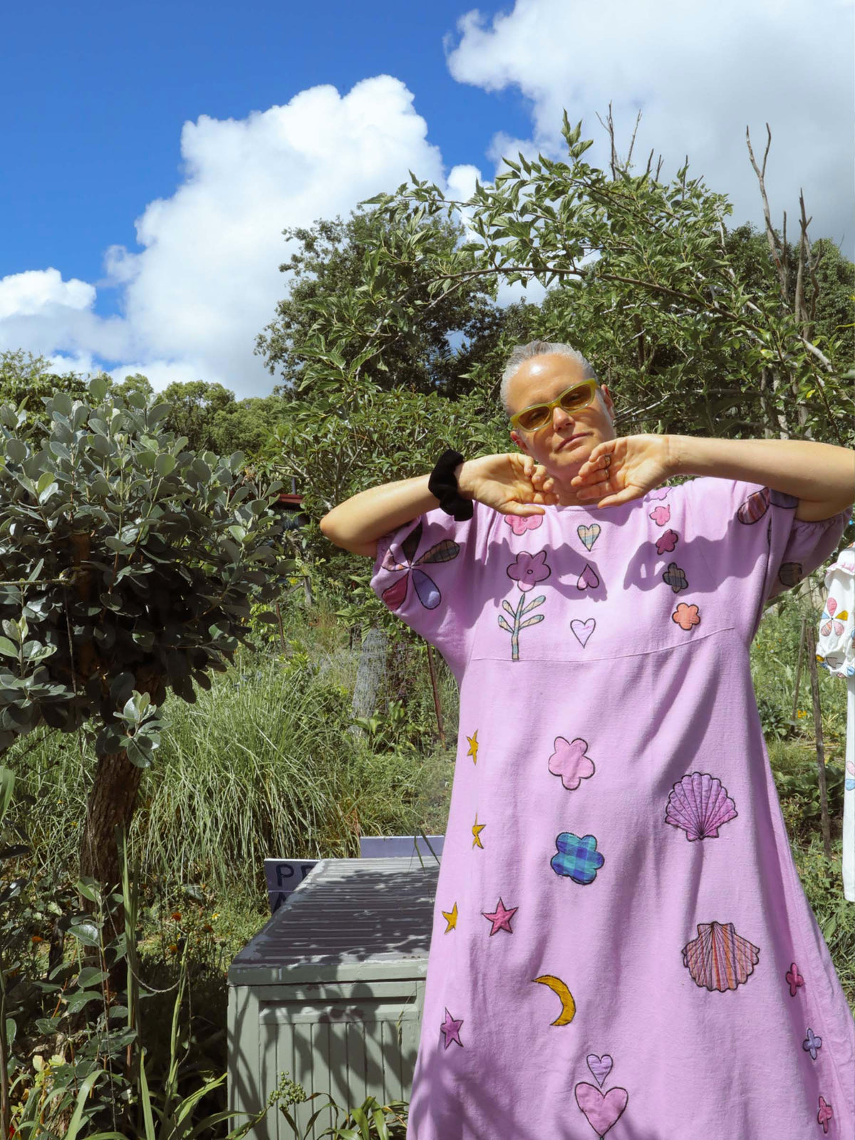 Person wearing a purple dress with colorful applique in an outdoor setting