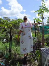 Load image into Gallery viewer, Person wearing a white dress with floral patterns in a garden setting