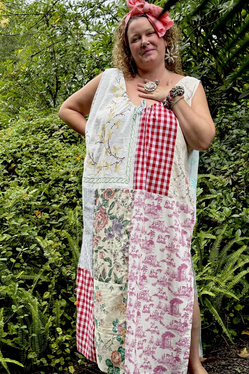 Woman wearing a patchwork dress with floral, checkered, and other patterns outdoors.