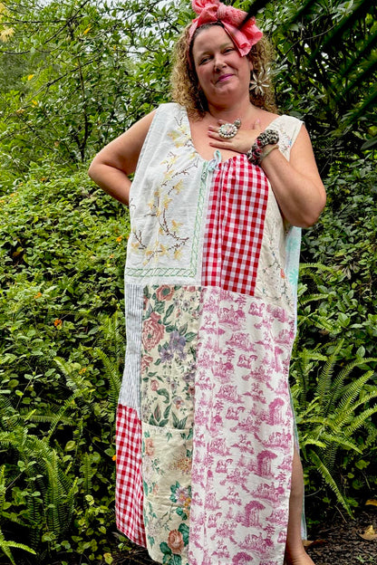 Woman wearing a patchwork dress with floral, checkered, and other patterns outdoors.