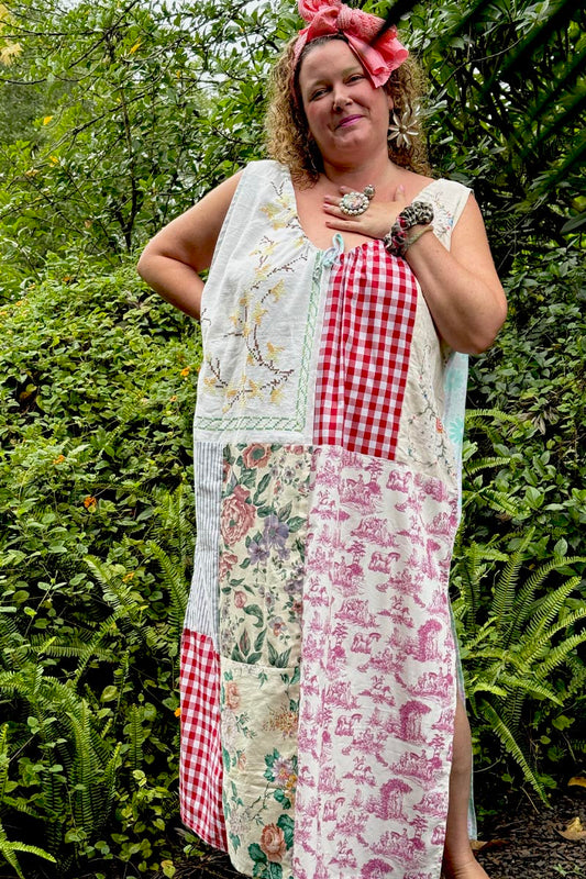 Woman wearing a patchwork dress with floral, checkered, and other patterns outdoors.