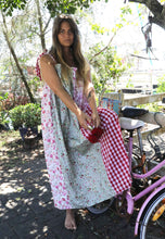 Load image into Gallery viewer, Woman in a floral dress holding a red flower next to a pink bicycle outdoors.