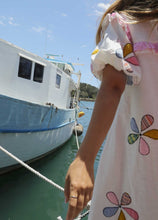 Load image into Gallery viewer, Person wearing a one size, plus size, bohemian white dress with colourful flower applique standing on a boat docked at a pier. Great Christmas Fashion Dress and black friday sale
