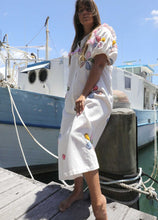 Load image into Gallery viewer, Person wearing a one size, plus size, bohemian white dress with colourful flower applique standing on a boat docked at a pier. Great Christmas Fashion Dress and black friday sale