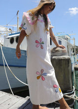 Load image into Gallery viewer, Person wearing a one size, plus size, bohemian white dress with colourful flower applique standing on a boat docked at a pier. Great Christmas Fashion Dress and black friday sale